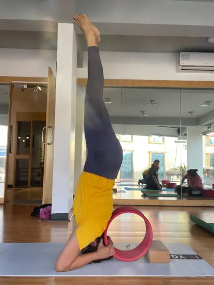 A supported headstand using the yoga wheel and blocks. Props make advanced inversions safer and more accessible.