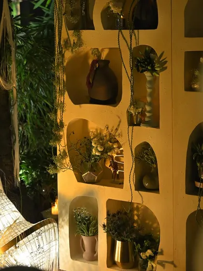 A unique decor wall with organically shaped niches, each holding a different floral arrangement or decorative vase. This custom piece adds an artistic and personal touch to the event.