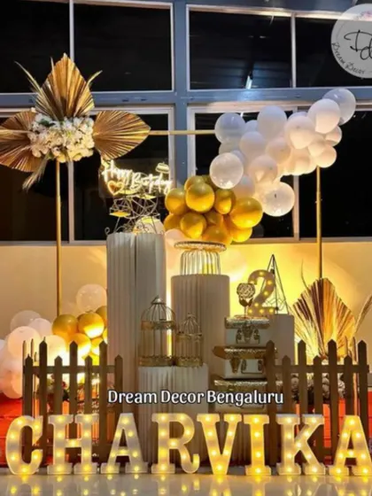 A classy and bohemian-inspired setup with a white and gold balloon garland, dried palm leaves, and elegant props.