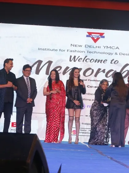 A student designer and her model receive an award for their collaborative effort on the runway.