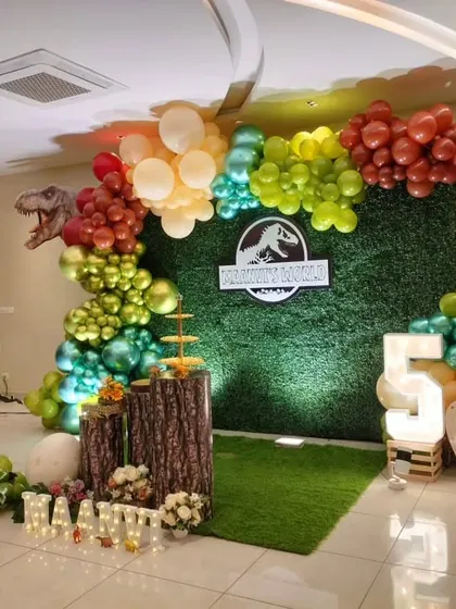 An alternate view of the dinosaur party setup, showing the complete balloon arch and prop arrangement.