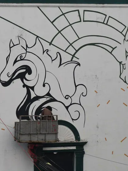 A shot of the horse mural in progress from below. You can see the scale of the artwork against the architecture of the building.