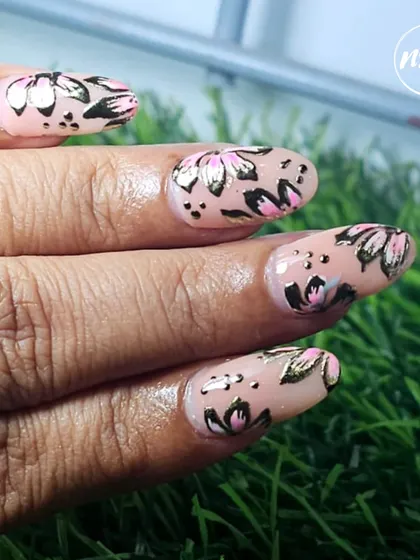 A close-up of a hand-painted floral design with gold foil accents. The combination of the soft pink flowers and the metallic gold gives this look a touch of modern elegance.