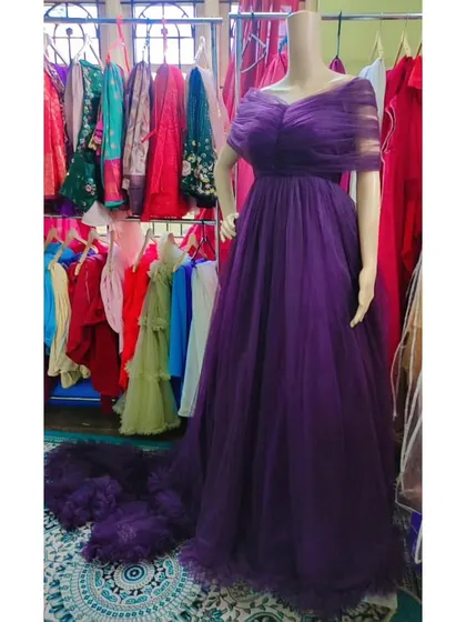 A deep purple off-shoulder maternity gown displayed on a mannequin. You can see the full trail and the elegant draped neckline.