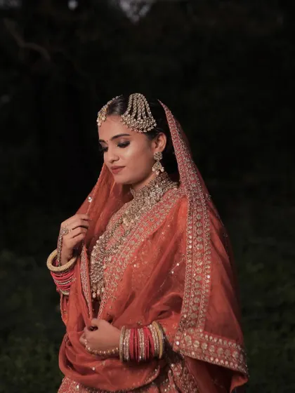 An ethereal shot capturing the bride's elegance. The makeup is kept classic with smoky eyes and a neutral lip to balance the vibrant color of her outfit.