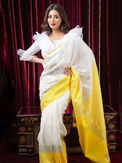 A classic white linen saree with a bright yellow border. This is a fresh and elegant combination, perfect for summer days, and can be styled for both casual and formal settings.