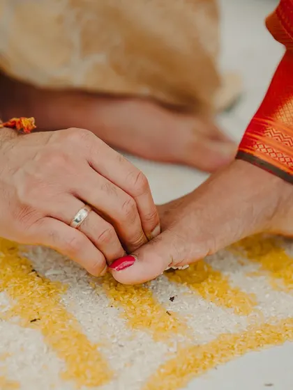 A close-up of the 'saptapadi' ritual, where the groom helps the bride touch the seven betel nuts with her toe, symbolizing the seven sacred vows.