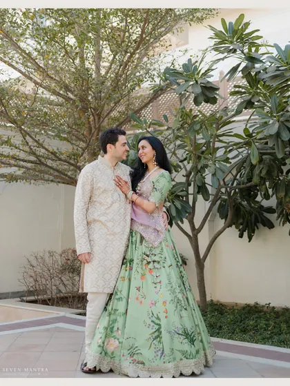 A full-length portrait set against the beautiful architecture and greenery, showcasing the couple in their stunning wedding attire.