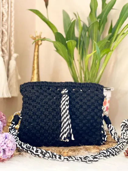 A classic black sling bag gets a modern twist with a contrasting black and white braided strap and a matching statement tassel. It's a versatile piece that goes with everything.