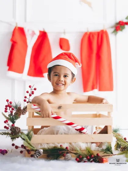 The perfect holiday portrait. This close-up from a Christmas themed session shows a happy boy in a Santa hat, holding a candy cane in a festive, custom-designed crate setup.
