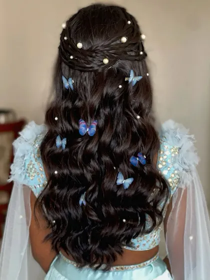 A whimsical hairstyle with a braided crown and cascading curls, filled with blue butterfly clips.