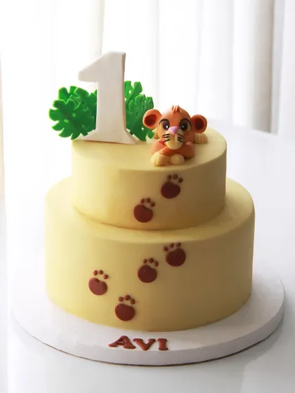 A simple and cute Simba-themed cake for Avi's 1st birthday, featuring the little lion cub and his paw prints.