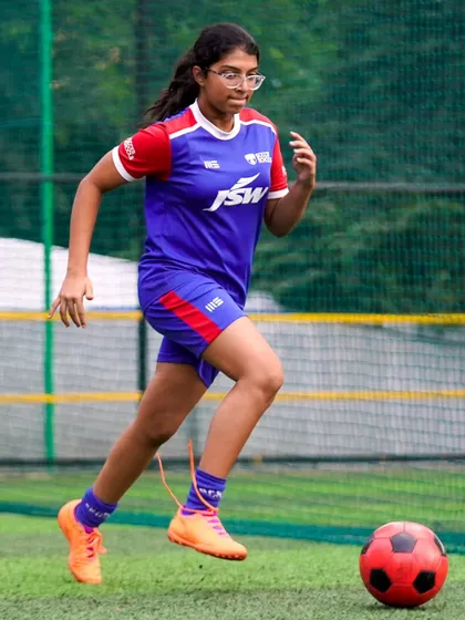 A young girl runs with the ball, showcasing her speed and determination. We are proud to support the development of female footballers.
