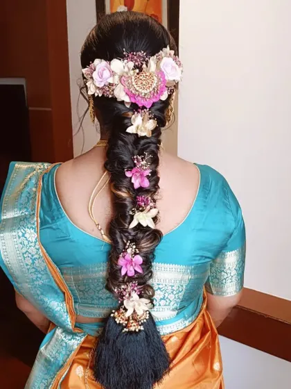A stunning fishtail braid adorned with a mix of fresh and artificial flowers in shades of pink and white.