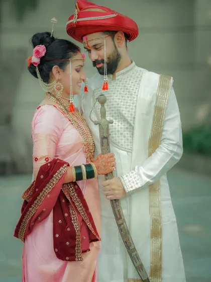 A classic wedding portrait with a focus on the couple's regal attire and the bride's beautiful jewelry.