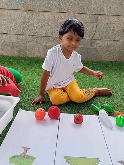 A teacher looks on as a child sorts vegetables, a great activity for developing scientific thinking and classification skills.