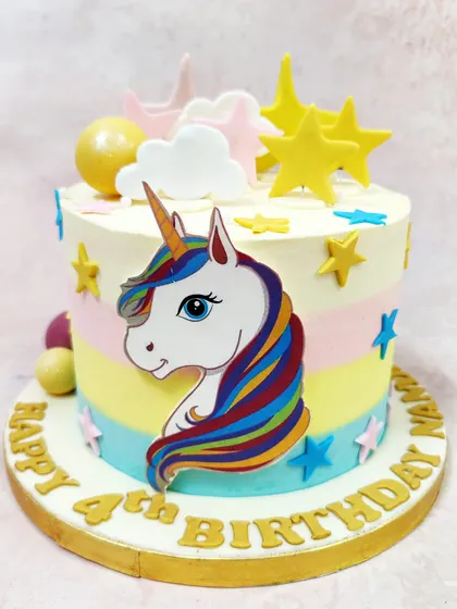 We make wishes come true with this enchanting celestial unicorn cake. A majestic unicorn is set against pastel rainbow stripes, surrounded by golden stars and fluffy clouds, creating a magical and dreamy birthday experience.