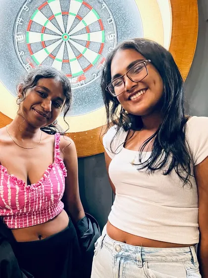Two friends posing by the dartboard during our lively Karaoke Friday. It's the perfect game to play between songs and drinks.