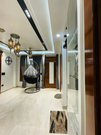 This living room corner features a hanging swing chair, creating a perfect spot for relaxation. The Moroccan-style pendant lights and dark curtains add to the cozy and intimate ambiance.