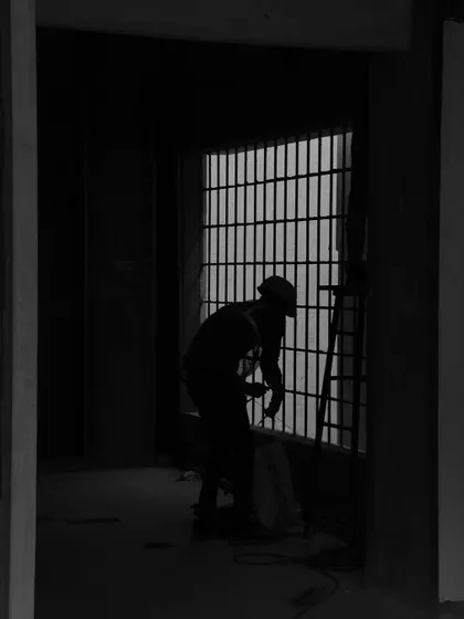 A powerful, monochrome silhouette of a worker on site. This artistic shot captures the focus and dedication of the individuals who build our spaces.