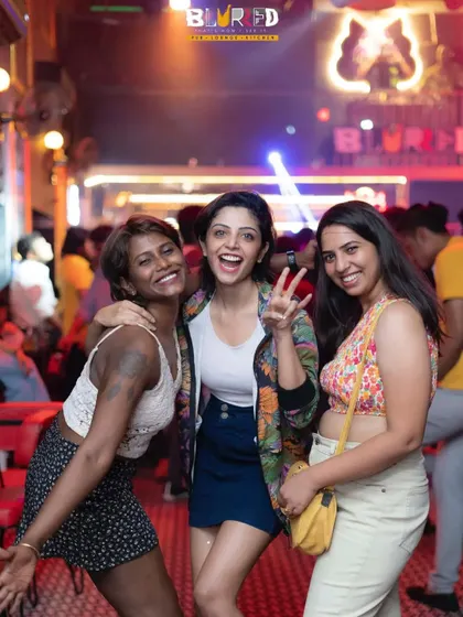 Three friends with big smiles, enjoying the vibrant atmosphere at Blurred lounge. My music brings out the joy in everyone.