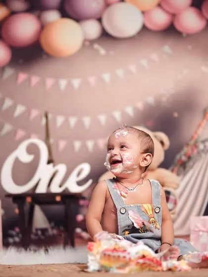 The pure joy of a first birthday cake smash. This little one's happy, messy face says it all, surrounded by a fun setup of balloons and presents.