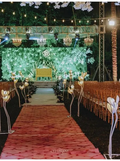 The view down the aisle towards a beautiful reception stage with a green foliage backdrop.