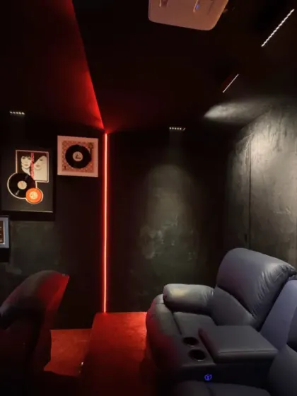 Another view of the home theater, focusing on the comfortable, deep-blue leather recliners and the subtle yet effective use of red LED strip lighting.