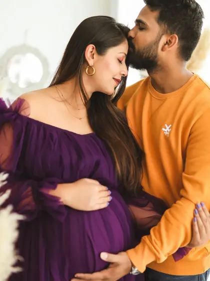 A warm and tender embrace between expecting parents. The husband's gentle kiss and their happy expressions perfectly capture the love and excitement of this special time.