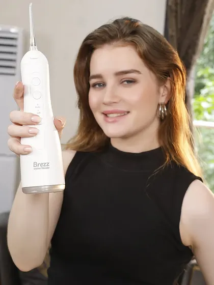 A clean, direct shot of the model presenting the white water flosser to the camera, perfect for a product landing page.