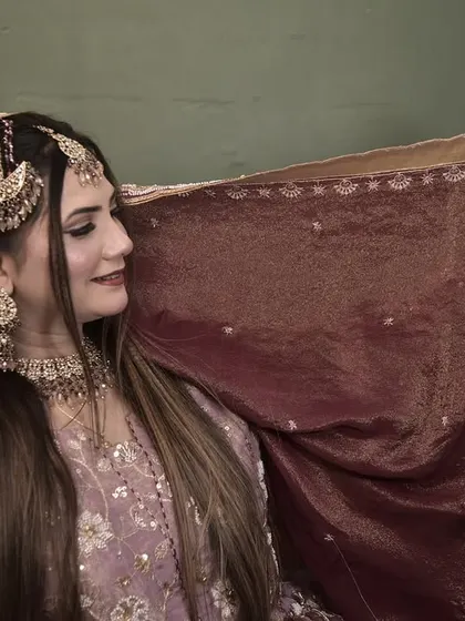 A playful moment with the dupatta. This shot gives a better view of her side-parted hairstyle and the elegant placement of her headpiece.