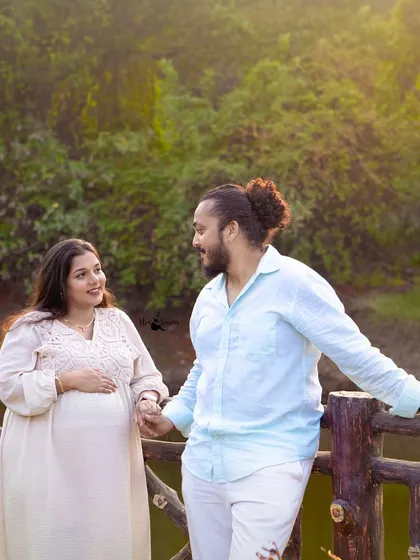 A candid moment of the couple sharing a look while holding hands. The warm, golden sunlight filtering through the trees adds a magical touch to this outdoor portrait.