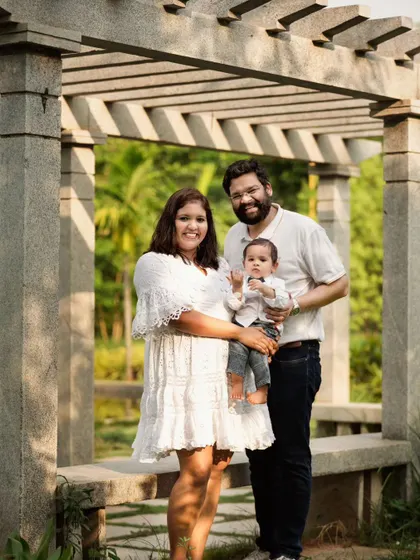 This wider shot from the same outdoor family session frames the family beautifully under a stone pergola. Using architectural elements adds structure and depth to outdoor portraits, creating a more formally composed yet still natural family photograph.