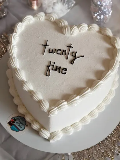 Simple, elegant, and perfect for any celebration. This heart-shaped cake with the message "twenty fine" features a classic piped border and minimalist design.