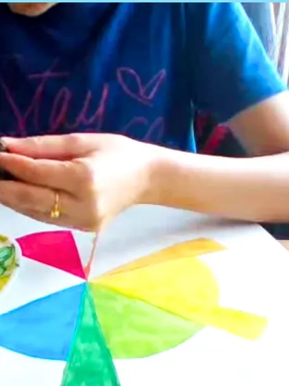 A student learning about the color wheel by painting segments with watercolors, a foundational exercise in color theory.