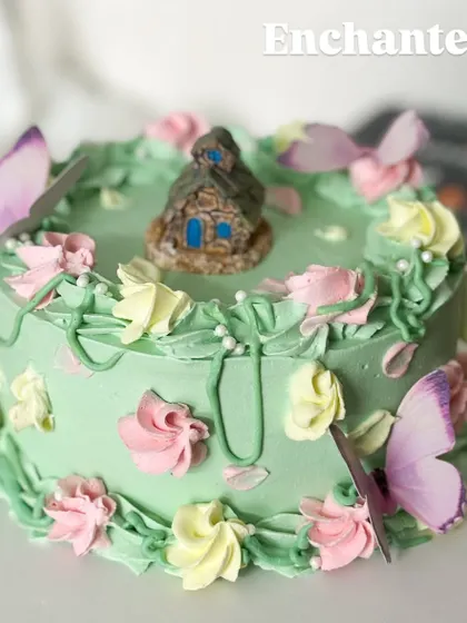 An enchanted forest on a cake. This whimsical design features a tiny house, delicate butterflies, and piped flowers, creating a magical world for a special celebration.