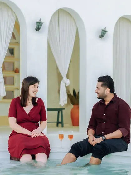 A relaxed and happy moment of a couple enjoying a drink by a Santorini-themed poolside in Jaipur, showing our versatility with different location styles.