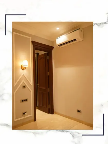 You deserve a masterpiece. This corner shows a solid wood door, elegant wall moulding, and a modern sconce, details that come together to create a feeling of refined luxury.