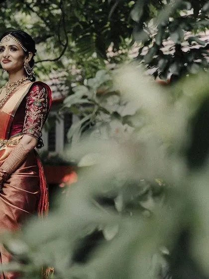 A beautiful bridal portrait with a soft, dreamy feel. The out of focus leaves in the foreground create a natural frame, drawing attention to the bride's serene expression.