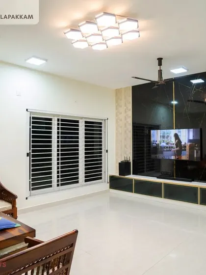 The living room in the Sithalapakkam villa, showcasing a large, dark marble-finish TV unit with gold inlays that serves as a dramatic focal point.