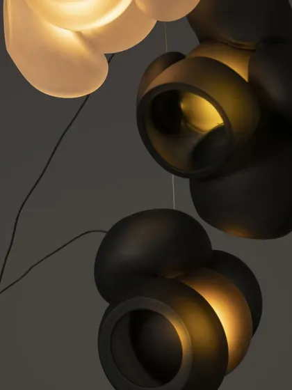 A close-up detail of the Bocci 100 series, showing the contrast between the matte black and translucent white glass. Each pendant is a unique result of the glassblowing process.