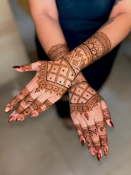 Jyotika's wedding mehendi, featuring intricate geometric check patterns and detailed borders that extend up the wrist.