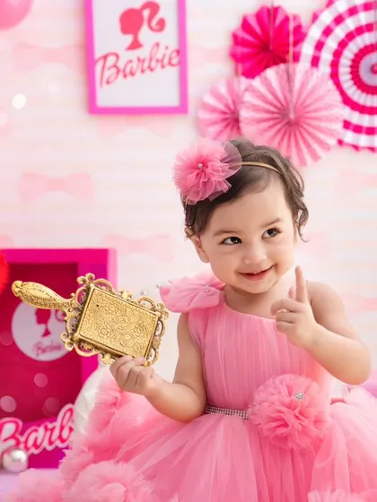 Come on Barbie, let's go party. This little girl gives a thumbs-up, fully embracing her fun and vibrant Barbie-themed birthday shoot.