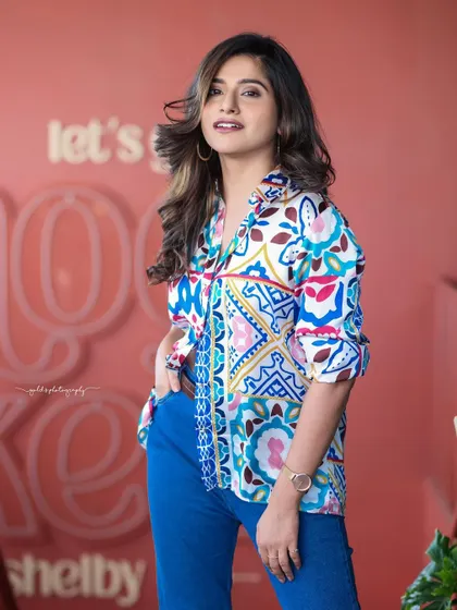 A lifestyle fashion shoot for an actress, featuring a colorful printed shirt and blue jeans. Shot in a modern cafe, these images have a bright, energetic, and youthful feel, perfect for a commercial or social media campaign.
