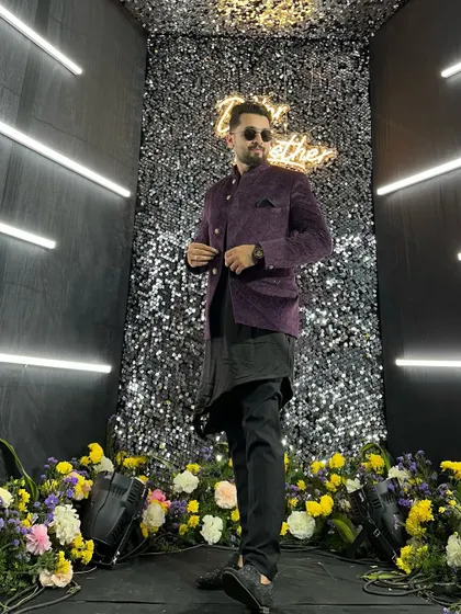Posing at a Sangeet night photo booth. The outfit, a purple bandhgala with an asymmetric kurta, is an example of the modern, stylish look I bring to evening events.