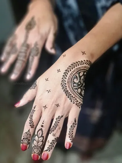 A simple yet striking half-mandala on the back of the hand, paired with leafy vines on the fingers.