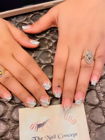 A delicate and modern design on short nails. The sheer base is decorated with a chevron pattern at the tips using fine silver glitter.