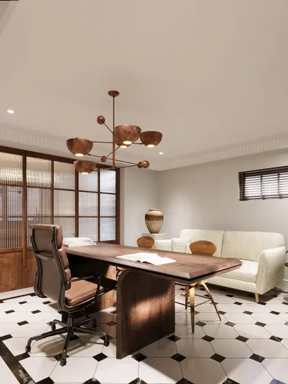 Another view of the home office, showing the balance of elements. A comfortable sofa provides a space for breaks, while the large desk offers ample workspace. The ribbed glass partition adds privacy without blocking light.