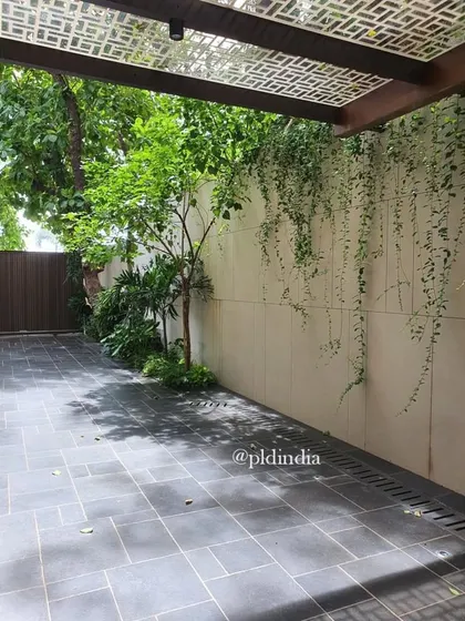 A simple yet elegant design featuring a wall of cascading vines. This creates a living green curtain that provides a beautiful backdrop for an open patio space, with a perforated canopy offering dappled sunlight.
