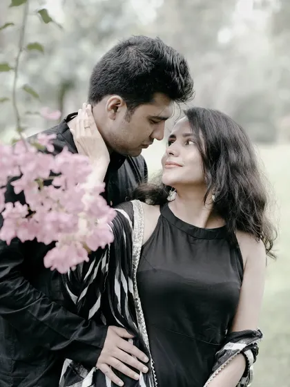 A classic romantic pose, with the couple looking into each other's eyes, surrounded by soft pink flowers.